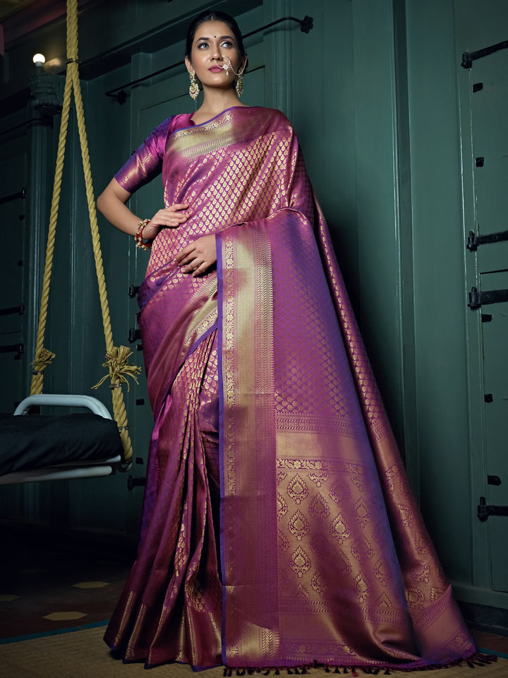 Model draped in a mauve purple Kanjeevaram saree with gold zari motifs and leaf-detail pallu.