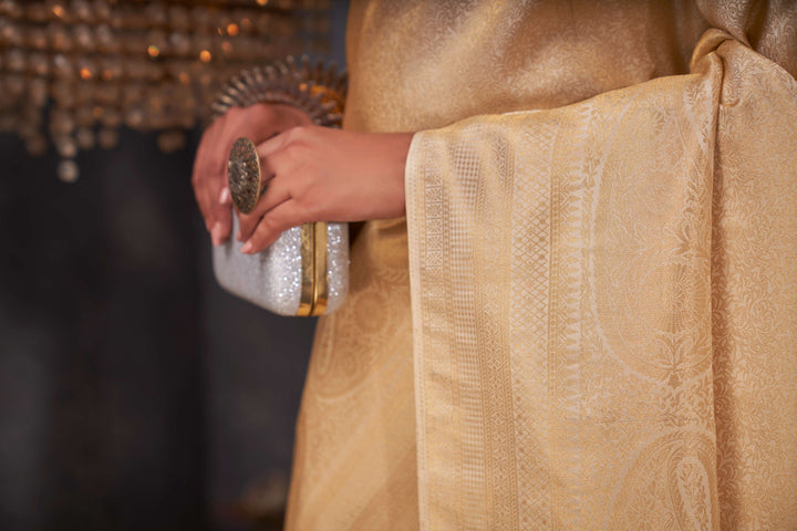 Close-up of gold zari motifs on the saree’s rich silk texture.