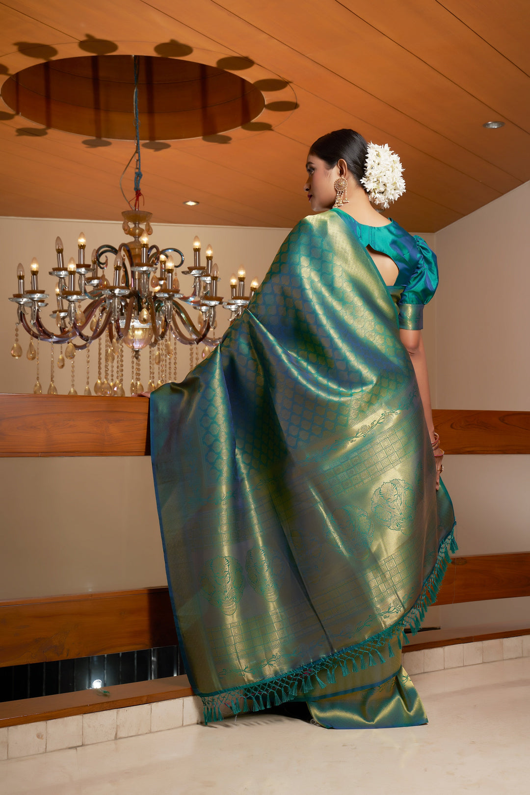 Back view of the model highlighting the zari-rich pallu and elegant fall of the saree.