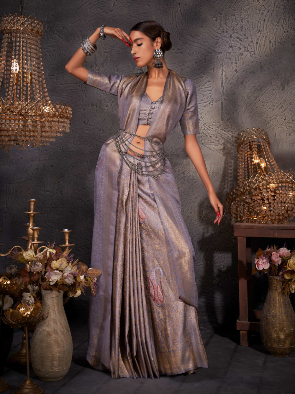 Model wearing slate grey Kanjeevaram saree with gold, silver, and copper zari detailing across the body and pallu.