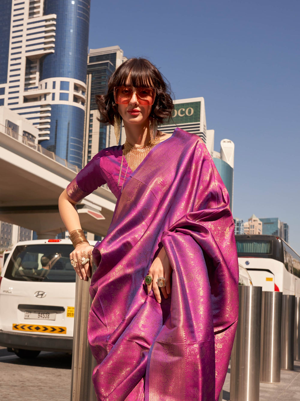 Glossy purple traditional saree in kanjivaram weave with shimmering gold zari work and bold aesthetic. Luxury silk saree with purple base and golden borders, party-ready ethnic wear with shine.