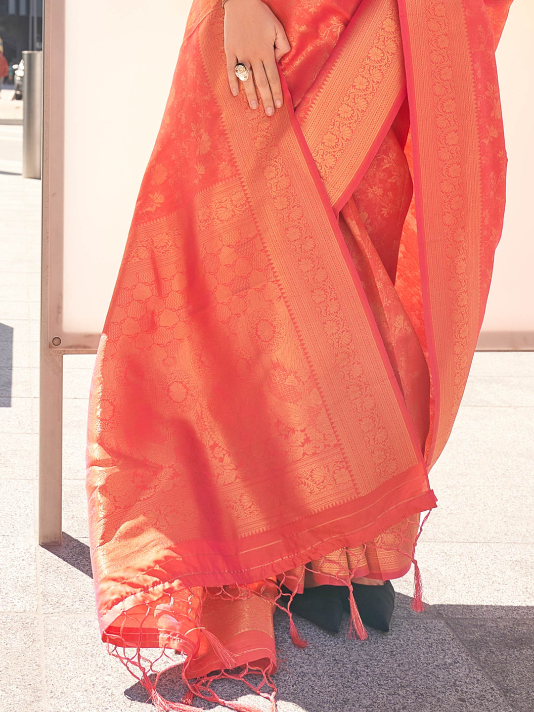 Statement silk saree in Coral–Gold tone with woven zari floral or paisley patterns. Coral–Gold festive saree with detailed motifs, paired with contrast blouse.