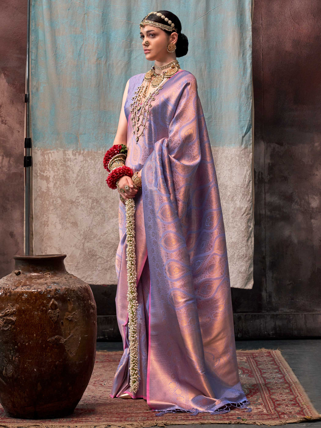 Lilac and Rose Gold two-tone handwoven silk saree with contrast selvage border and paisley weaving. This image captures the front drape view highlighting pallu fall and pleats alignment, ideal for visualizing festive elegance, designer appeal, and modern styling inspiration. Perfect for online shoppers seeking detailed previews before purchase, enhancing saree visual merchandising and SEO-rich product display strategy.                                                                                          