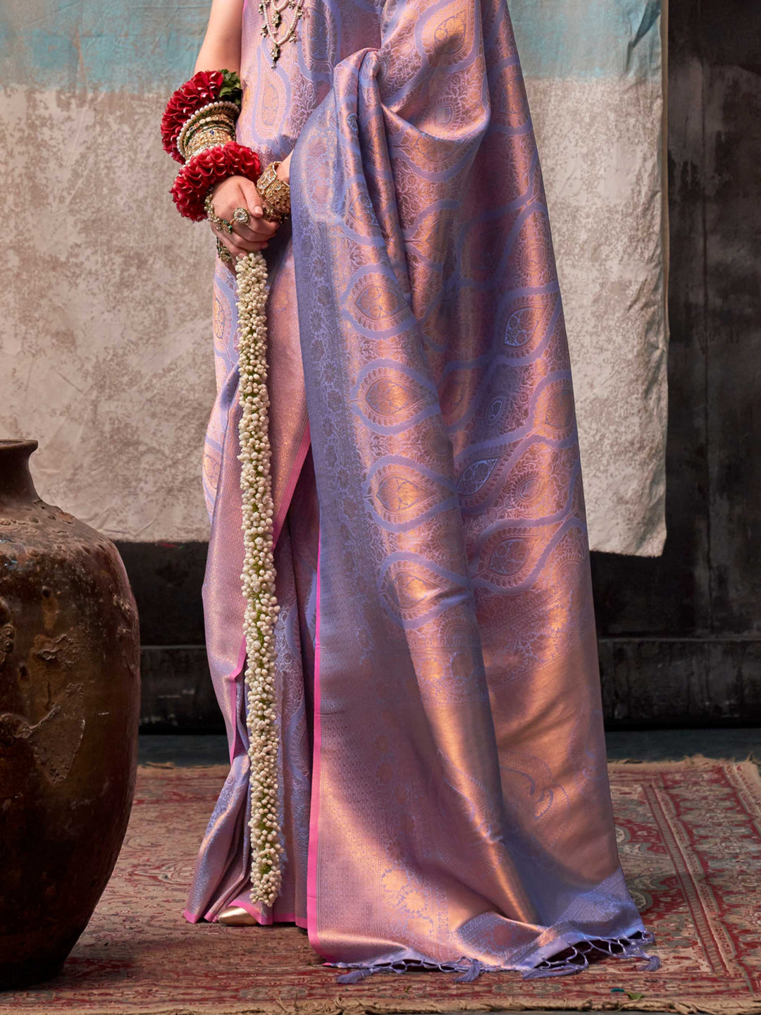 Lilac and Rose Gold two-tone handwoven silk saree with contrast selvage border and paisley weaving. This image captures the back drape focus revealing pallu finesse and motif richness, ideal for visualizing festive elegance, designer appeal, and modern styling inspiration. Perfect for online shoppers seeking detailed previews before purchase, enhancing saree visual merchandising and SEO-rich product display strategy.                                                                                            