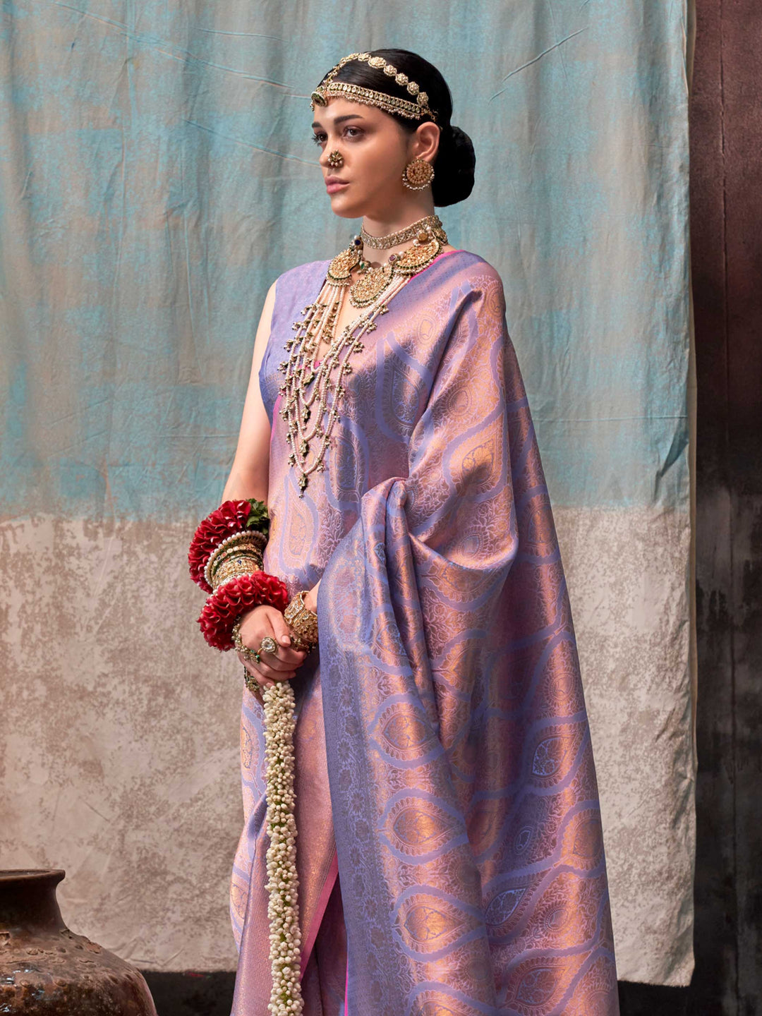 Lilac and Rose Gold two-tone handwoven silk saree with contrast selvage border and paisley weaving. This image captures the side angle view showcasing blouse styling and zari border detail, ideal for visualizing festive elegance, designer appeal, and modern styling inspiration. Perfect for online shoppers seeking detailed previews before purchase, enhancing saree visual merchandising and SEO-rich product display strategy.                                                                                       