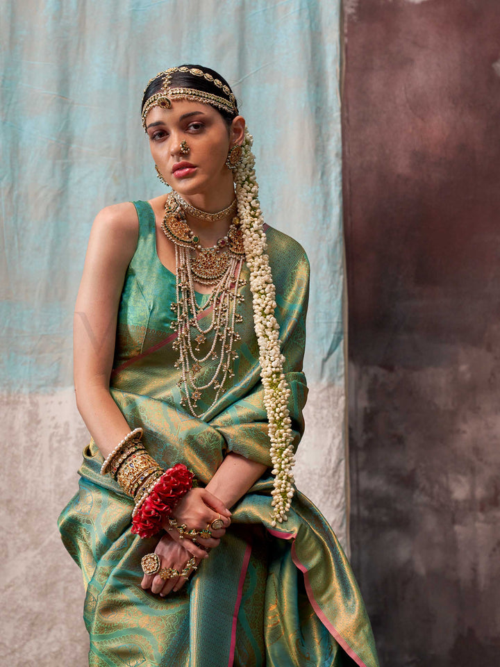 Green and Gold two-tone handwoven silk saree with contrast selvage border and paisley weaving. This image captures the walking motion view showcasing fluid drape and festive movement, ideal for visualizing festive elegance, designer appeal, and modern styling inspiration. Perfect for online shoppers seeking detailed previews before purchase, enhancing saree visual merchandising and SEO-rich product display strategy.                                                                                             