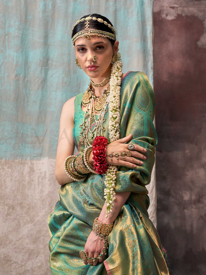 Green and Gold two-tone handwoven silk saree with contrast selvage border and paisley weaving. This image captures the pleats close-up showing symmetry, color blending, and craftsmanship, ideal for visualizing festive elegance, designer appeal, and modern styling inspiration. Perfect for online shoppers seeking detailed previews before purchase, enhancing saree visual merchandising and SEO-rich product display strategy.                                                                                         