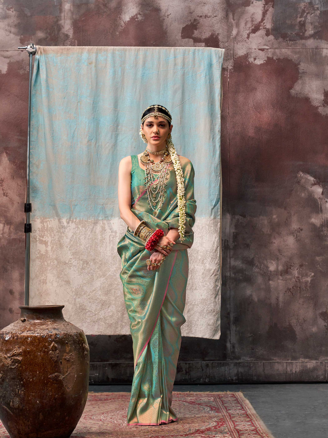 Green and Gold two-tone handwoven silk saree with contrast selvage border and paisley weaving. This image captures the model styling perspective with complete saree ensemble displayed, ideal for visualizing festive elegance, designer appeal, and modern styling inspiration. Perfect for online shoppers seeking detailed previews before purchase, enhancing saree visual merchandising and SEO-rich product display strategy.                                                                                            