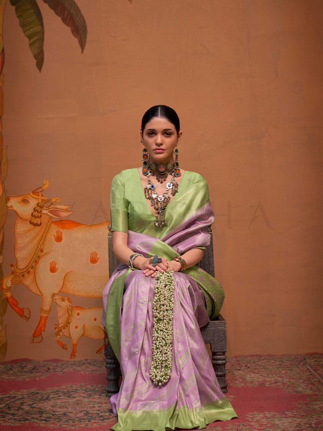 Lavender and Pista Green striped silk saree with handloom weave and checked pallu. Ideal for sangeet functions like sister of bride, styled with heritage jewelry and temple-inspired accessories. This image captures the model styling perspective with complete saree ensemble displayed, ideal for visualizing festive elegance, designer appeal, and modern styling inspiration. Perfect for online shoppers seeking detailed previews before purchase, enhancing saree visual merchandising and SEO-rich product display s