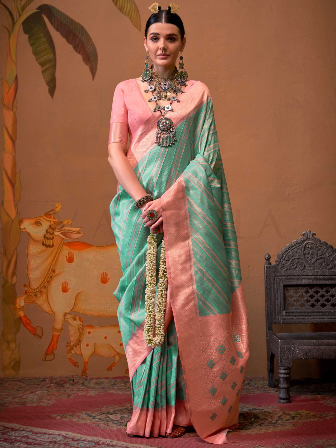 Mint Green and Blush Peach striped silk saree with handloom weave and checked pallu. Ideal for party-wear functions like cultural events, styled with heritage jewelry and temple-inspired accessories. This image captures the model styling perspective with complete saree ensemble displayed, ideal for visualizing festive elegance, designer appeal, and modern styling inspiration. Perfect for online shoppers seeking detailed previews before purchase, enhancing saree visual merchandising and SEO-rich product disp