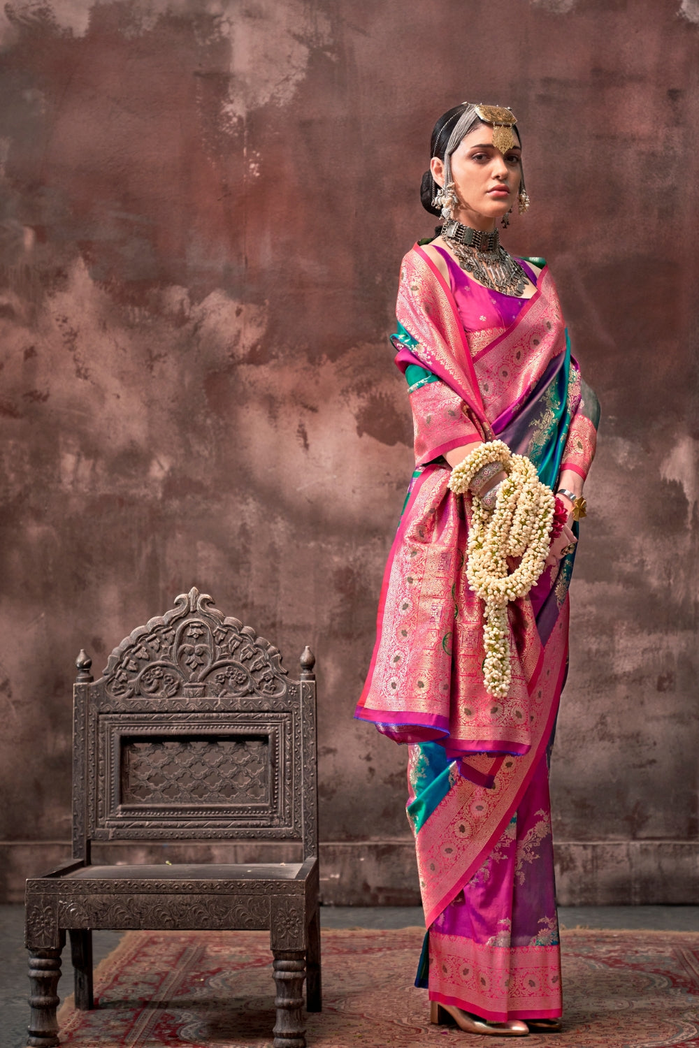 Fuchsia and Teal Blue Rangkaat silk saree with temple borders, intricate zari pallu, and traditional wedding styling. Handloom drape perfect for bollywood functions and magazine shoot, styled with mogra, antique jewelry, and regal stance. This image captures the model styling perspective with complete saree ensemble displayed, ideal for visualizing festive elegance, designer appeal, and modern styling inspiration. Perfect for online shoppers seeking detailed previews before purchase, enhancing saree visual 