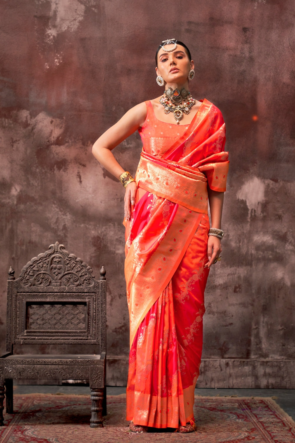 Vermilion Orange and Gold Rangkaat silk saree with temple borders, intricate zari pallu, and traditional wedding styling. Handloom drape perfect for wedding functions and engagement or muhurtham, styled with mogra, antique jewelry, and regal stance. This image captures the model styling perspective with complete saree ensemble displayed, ideal for visualizing festive elegance, designer appeal, and modern styling inspiration. Perfect for online shoppers seeking detailed previews before purchase, enhancing sa