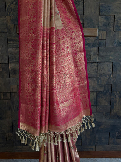 Traditional pink and beige patterned fabric with tassels against a stone wall.