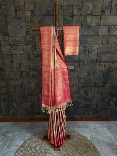 Red and gold saree with a wooden stand against a textured wall.
