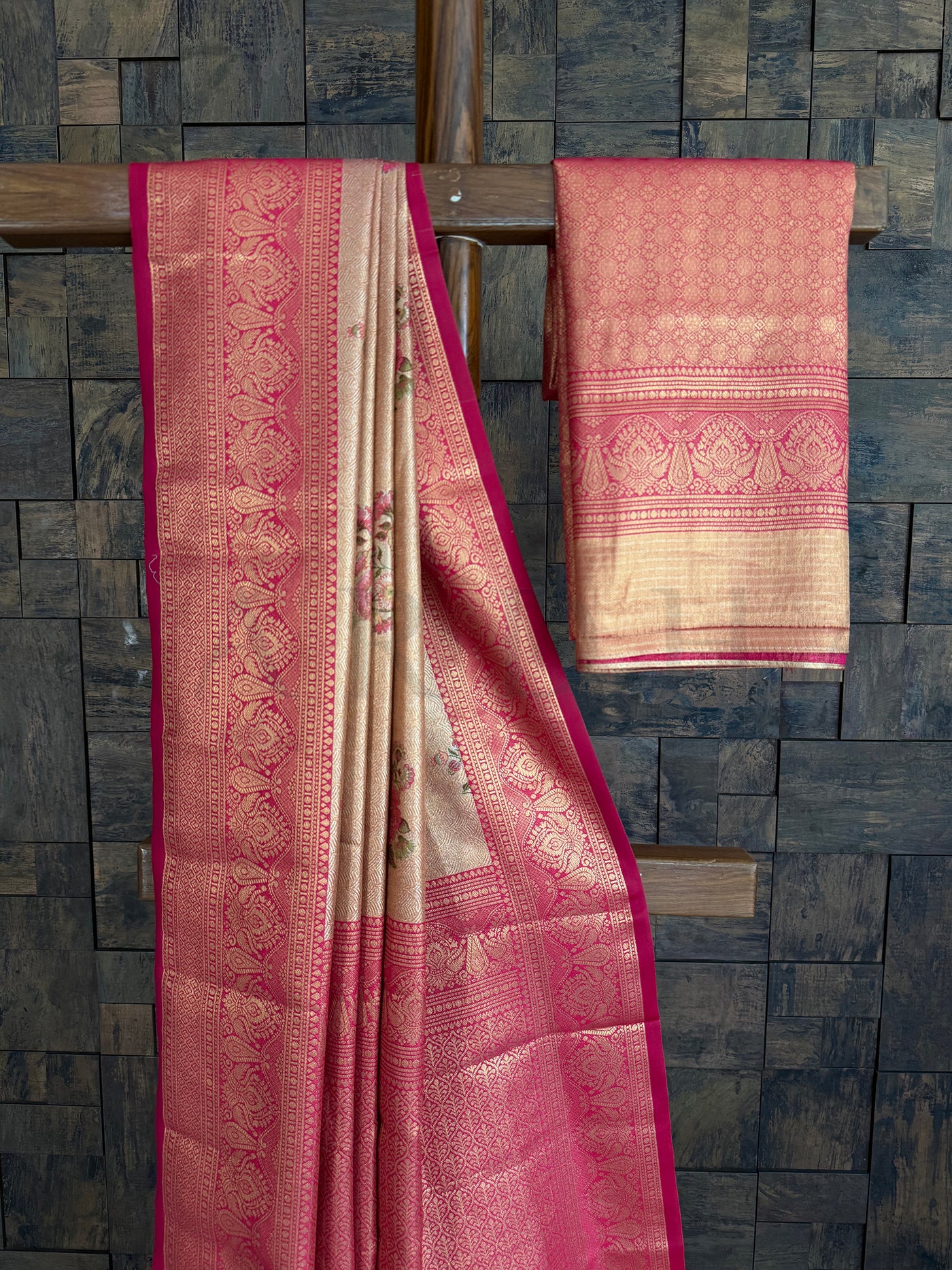 Pink and beige saree with intricate patterns on a stone wall background