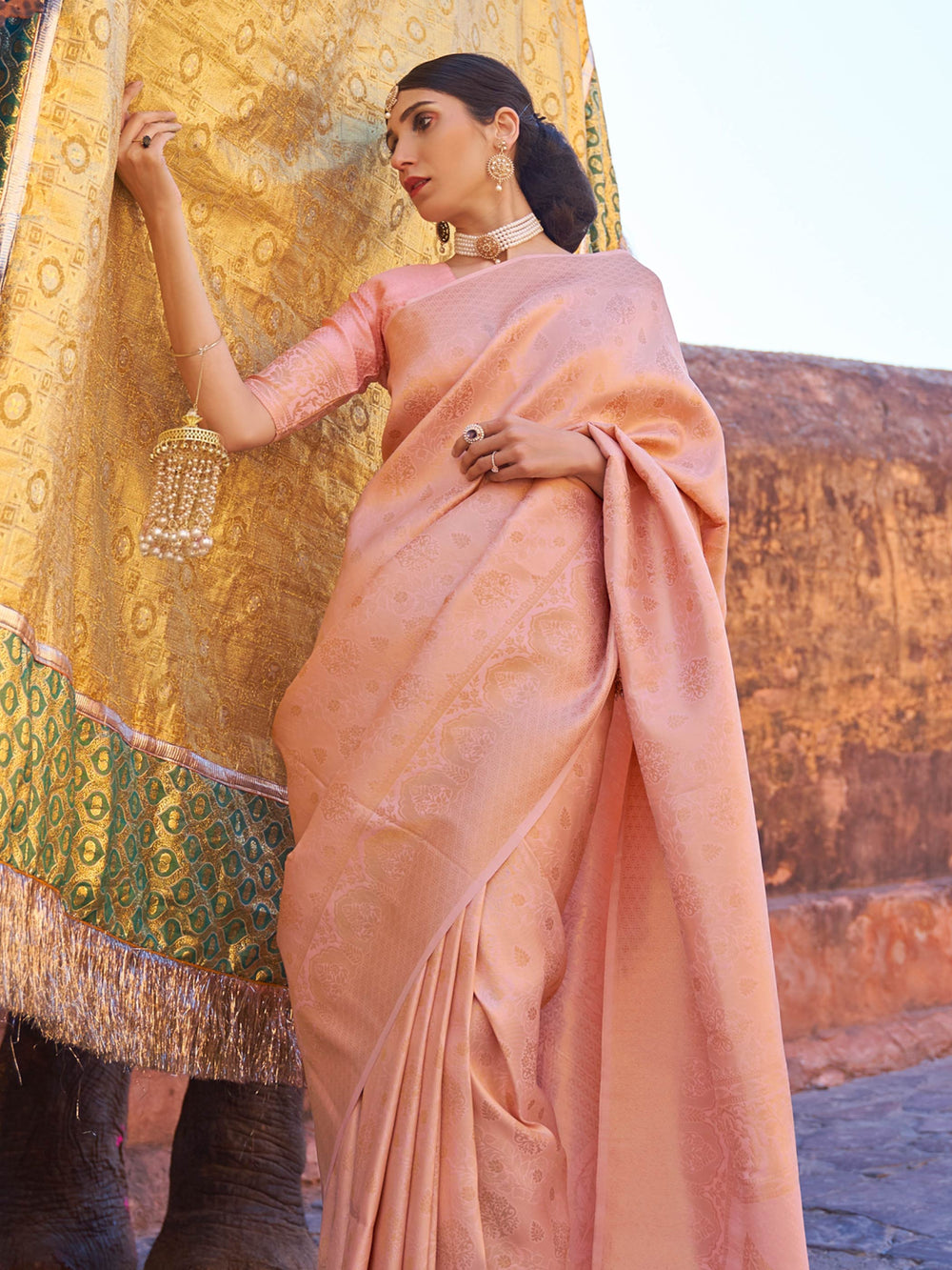 Graceful Peach–Gold ethnic saree with soft kanjivaram texture for traditional events. Zari detailed silk saree in Peach–Gold, styled for day weddings and sangeet functions.