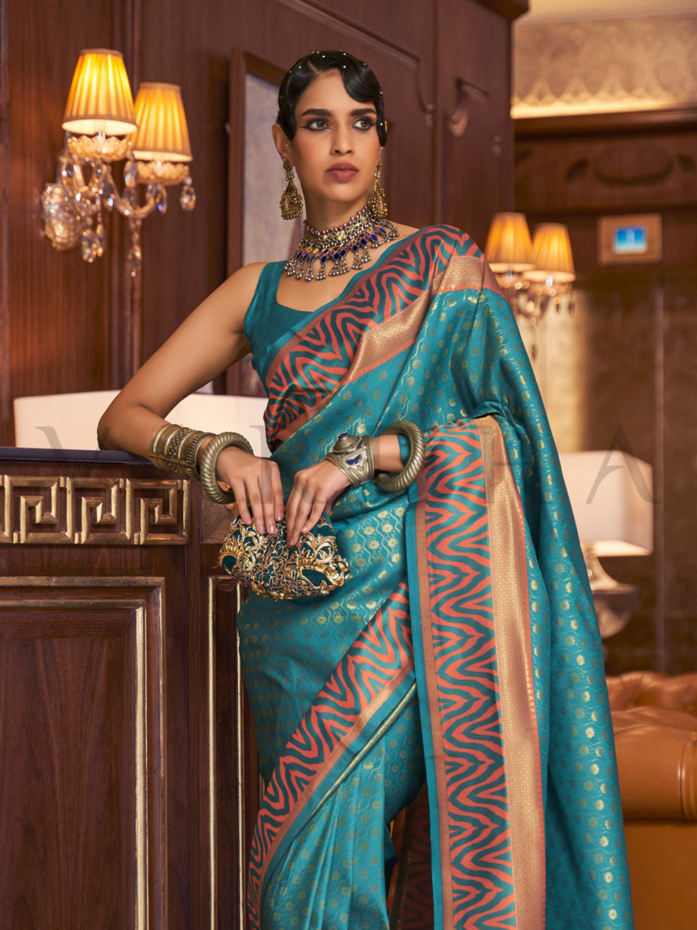 This luxurious Teal Blue–Copper Kanjivaram Silk saree features classic woven zari work with contrast pallu and ornate detailing. Elegant wedding attire with heritage style and timeless drape. SKU 271001. This luxurious Teal Blue–Copper Kanjivaram Silk saree features classic woven zari work with contrast pallu and ornate detailing. Elegant wedding attire with heritage style and timeless drape. SKU 271001.