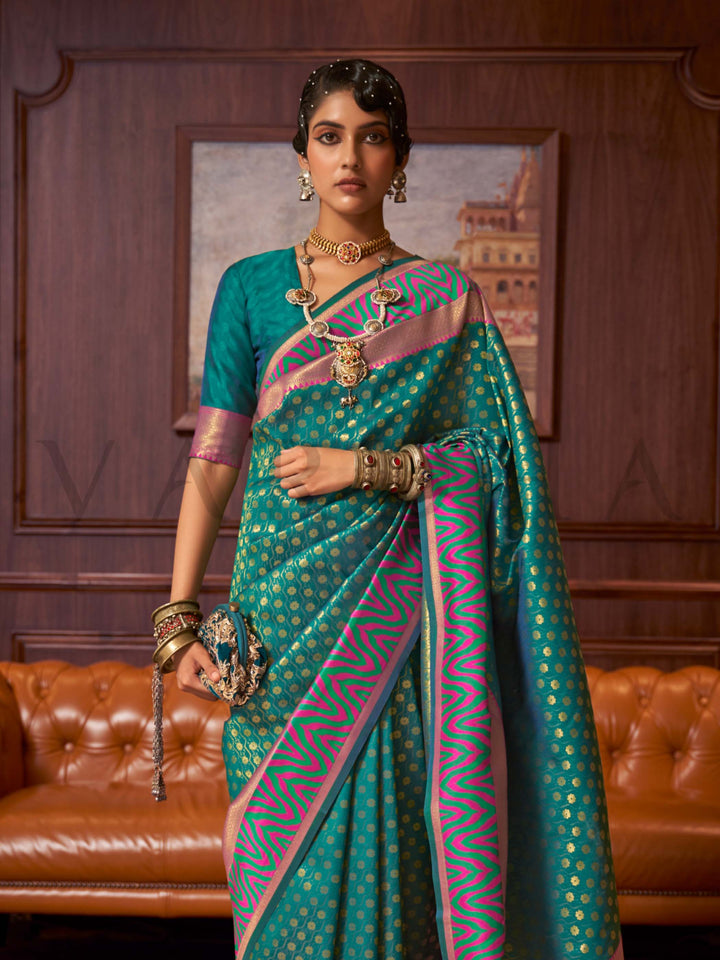 This luxurious Emerald Teal–Pink Kanjivaram Silk saree features classic woven zari work with contrast pallu and ornate detailing. Elegant wedding attire with heritage style and timeless drape. SKU 271006. This luxurious Emerald Teal–Pink Kanjivaram Silk saree features classic woven zari work with contrast pallu and ornate detailing. Elegant wedding attire with heritage style and timeless drape. SKU 271006.