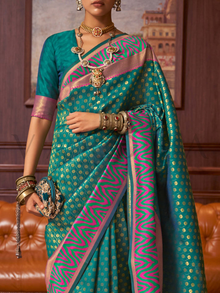 This luxurious Emerald Teal–Pink Kanjivaram Silk saree features classic woven zari work with contrast pallu and ornate detailing. Elegant wedding attire with heritage style and timeless drape. SKU 271006. This luxurious Emerald Teal–Pink Kanjivaram Silk saree features classic woven zari work with contrast pallu and ornate detailing. Elegant wedding attire with heritage style and timeless drape. SKU 271006.