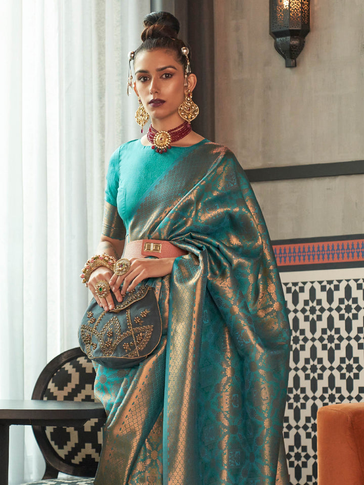 Teal Blue–Antique Gold silk saree featuring temple borders, zari detailing and dual-tone richness. Wedding-ready kanjivaram saree in Teal Blue–Antique Gold styled with regal accessories and clutch.