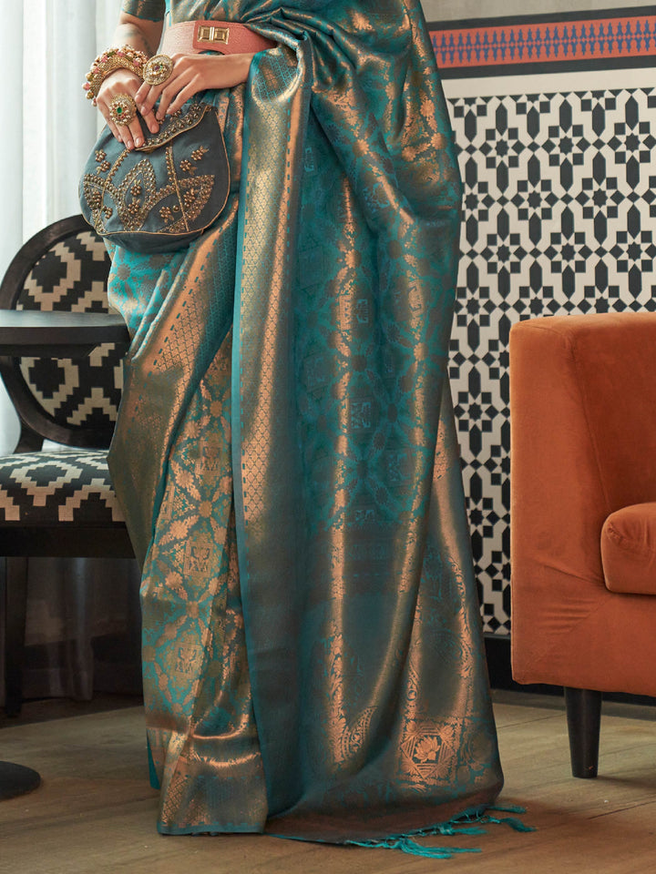 Glossy kanjivaram weave in Teal Blue–Antique Gold with intricate pallu motifs and elegant fall. Classic Teal Blue–Antique Gold bridal saree in silk with woven zari pallu and tassel finish.