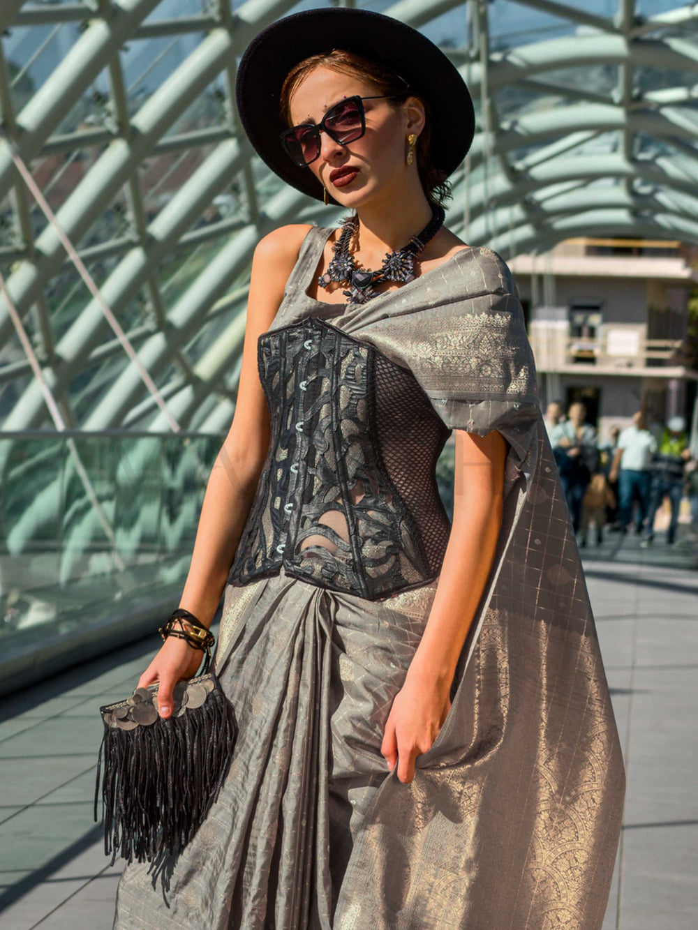 Champagne Grey Katan silk saree with Matte Silver zari detailing, featuring checks handloom weaving, designer blouse and tasselled pallu — a perfect fit for bollywood and award nights. Styled with modern belts, hats, and accessories to blend heritage and couture elegance. This image captures the side angle view showcasing blouse styling and zari border detail, ideal for visualizing festive elegance, designer appeal, and modern styling inspiration. Perfect for online shoppers seeking detailed previews before
