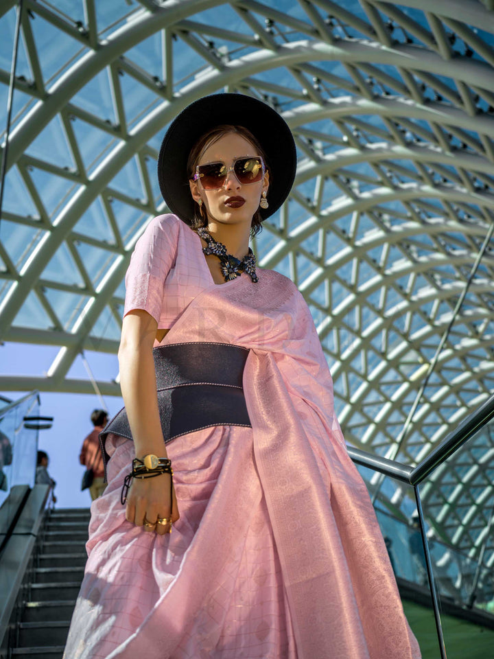 Blush Nude Katan silk saree with Ivory zari detailing, featuring checks handloom weaving, designer blouse and tasselled pallu — a perfect fit for party-wear and anniversary glam. Styled with modern belts, hats, and accessories to blend heritage and couture elegance. This image captures the model styling perspective with complete saree ensemble displayed, ideal for visualizing festive elegance, designer appeal, and modern styling inspiration. Perfect for online shoppers seeking detailed previews before purch