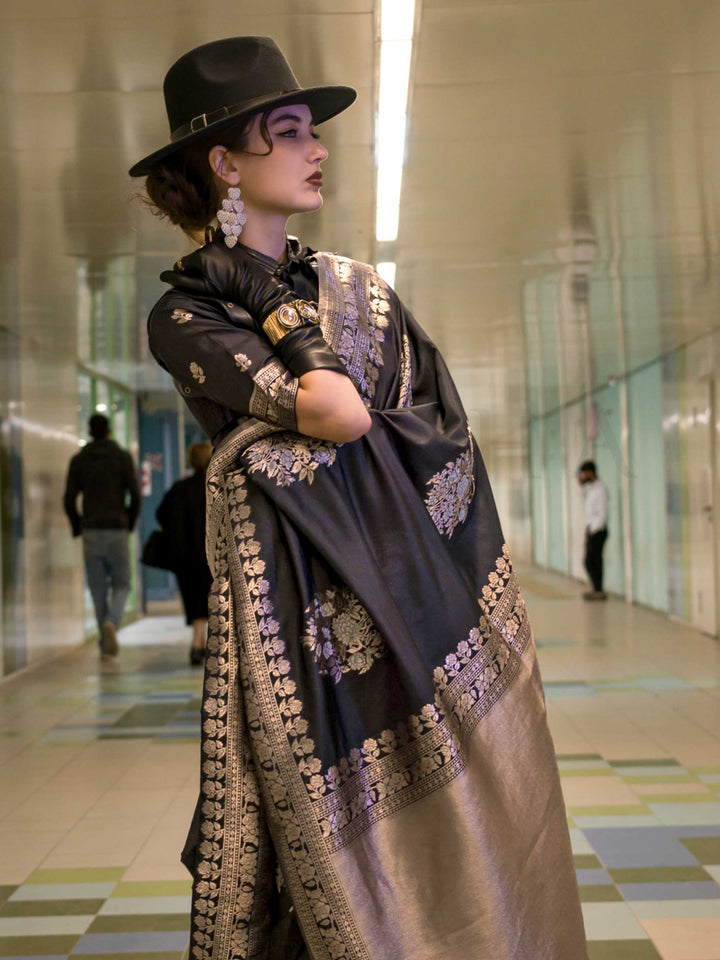 Jet Black silk saree with Old Gold Zari zari and Antique Beige floral motifs, styled with contrast blouse, handloom weaving, festive-ready look with cinematic silhouette and bold accessories — ideal for events and grand celebrations. This image captures the side angle view showcasing blouse styling and zari border detail, ideal for visualizing festive elegance, designer appeal, and modern styling inspiration. Perfect for online shoppers seeking detailed previews before purchase, enhancing saree visual merch