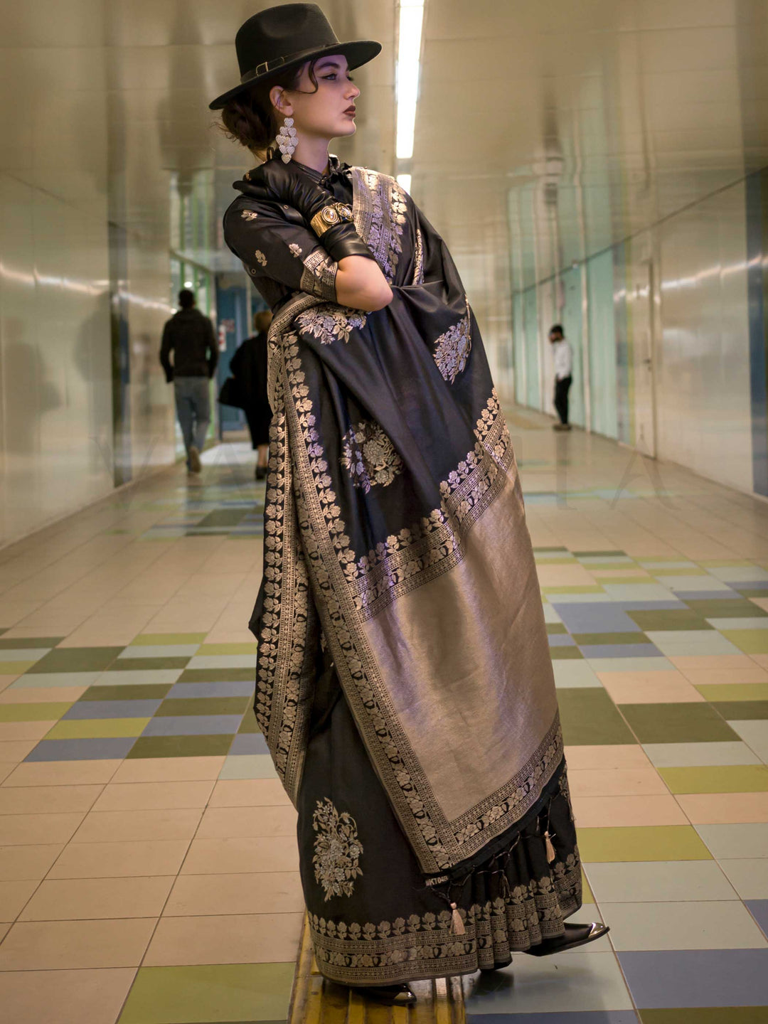 Jet Black silk saree with Old Gold Zari zari and Antique Beige floral motifs, styled with contrast blouse, handloom weaving, festive-ready look with cinematic silhouette and bold accessories — ideal for events and grand celebrations. This image captures the front drape view highlighting pallu fall and pleats alignment, ideal for visualizing festive elegance, designer appeal, and modern styling inspiration. Perfect for online shoppers seeking detailed previews before purchase, enhancing saree visual merchand