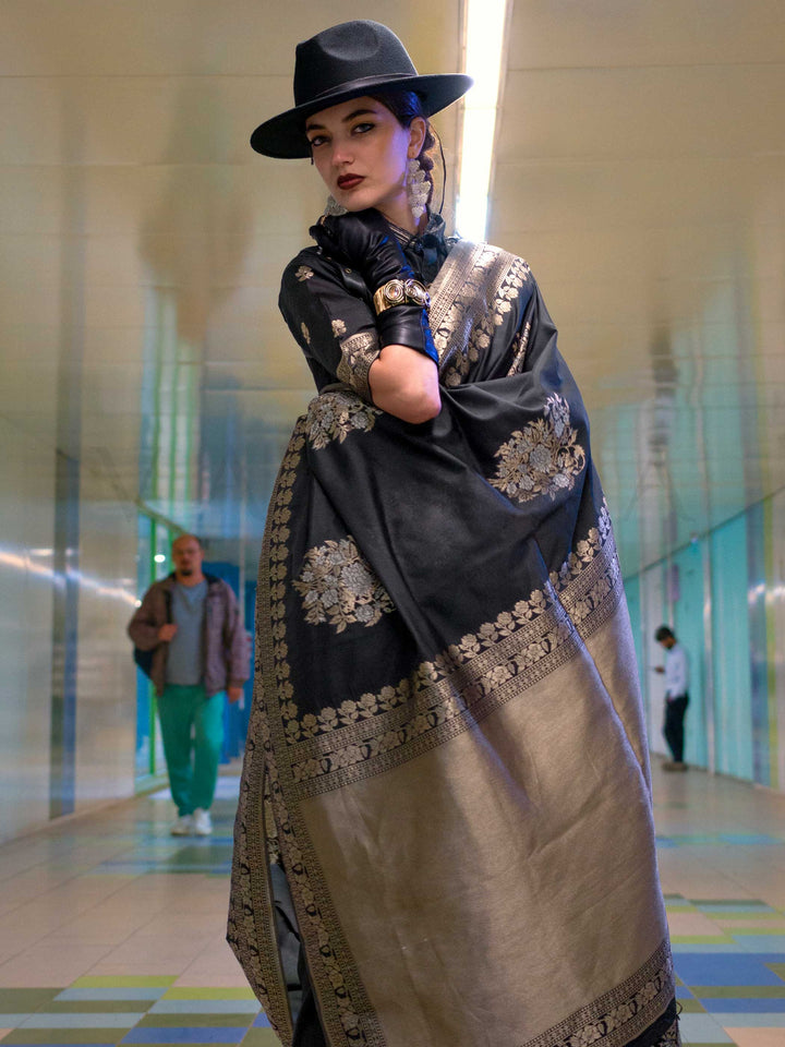 Jet Black silk saree with Old Gold Zari zari and Antique Beige floral motifs, styled with contrast blouse, handloom weaving, festive-ready look with cinematic silhouette and bold accessories — ideal for events and grand celebrations. This image captures the model styling perspective with complete saree ensemble displayed, ideal for visualizing festive elegance, designer appeal, and modern styling inspiration. Perfect for online shoppers seeking detailed previews before purchase, enhancing saree visual merch