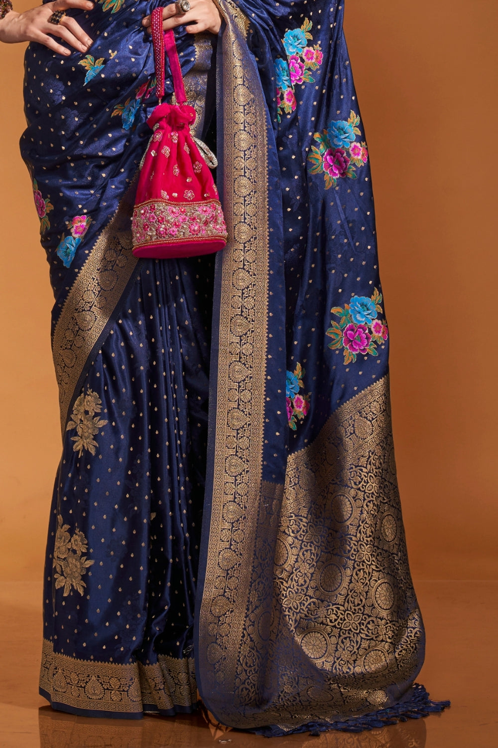 Navy Blue pure satin silk saree with multicolour floral handloom weaving and rich zari border. Styled for wedding and perfect for reception night, blending regal silk elegance with festive florals. This image captures the side angle view showcasing blouse styling and zari border detail, ideal for visualizing festive elegance, designer appeal, and modern styling inspiration. Perfect for online shoppers seeking detailed previews before purchase, enhancing saree visual merchandising and SEO-rich product displa