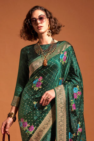 Bottle Green pure satin silk saree with multicolour floral handloom weaving and rich zari border. Styled for sangeet and perfect for evening bride entry, blending regal silk elegance with festive florals. This image captures the front drape view highlighting pallu fall and pleats alignment, ideal for visualizing festive elegance, designer appeal, and modern styling inspiration. Perfect for online shoppers seeking detailed previews before purchase, enhancing saree visual merchandising and SEO-rich product di
