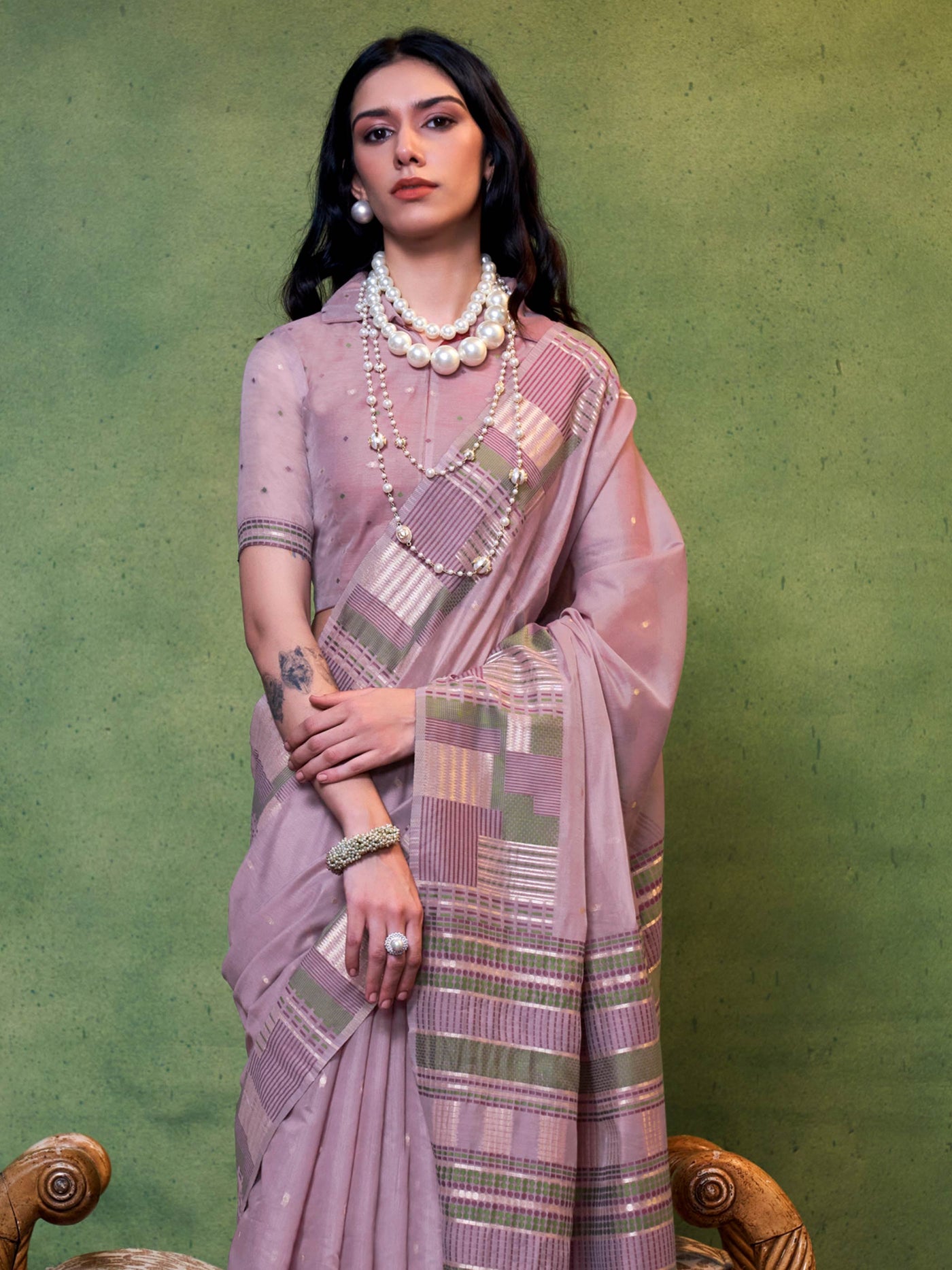 Dusty Mauve–Olive festive saree featuring woven checks, tassel finish, and soft pastel elegance. Pastel Dusty Mauve–Olive cotton saree for cultural daywear with minimalistic woven detailing.