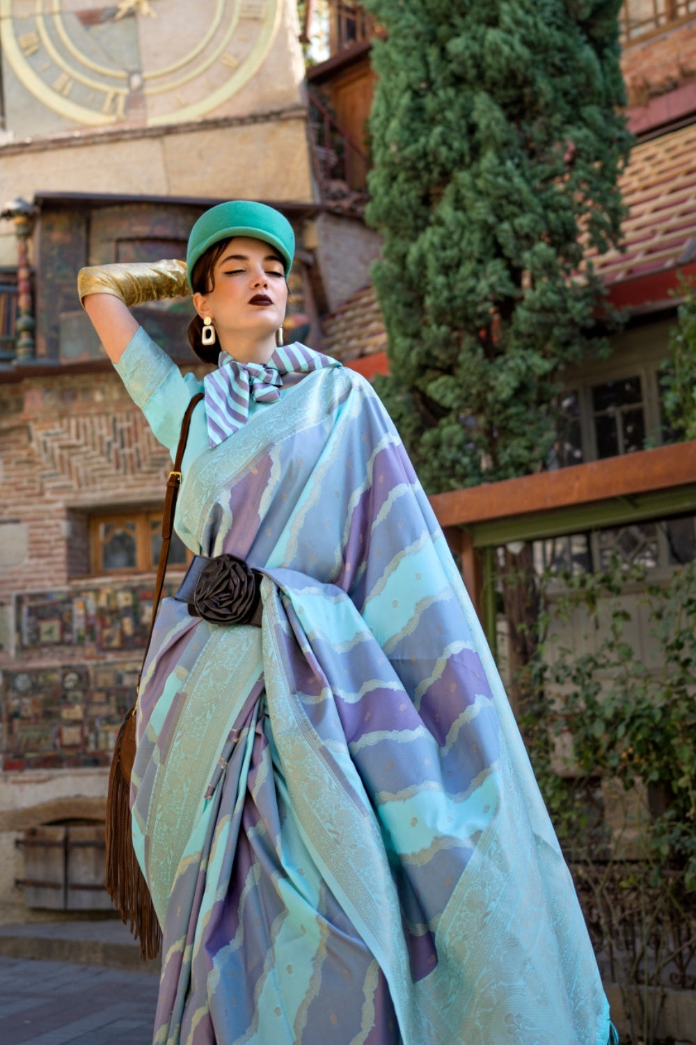 Teal Blue and Lavender Kimbus saree in rangkaat katan silk, designed with wave-striped motifs and a dramatic tassel pallu. Best styled for bollywood and fashion-forward red carpet celebrations. This image captures the model styling perspective with complete saree ensemble displayed, ideal for visualizing festive elegance, designer appeal, and modern styling inspiration. Perfect for online shoppers seeking detailed previews before purchase, enhancing saree visual merchandising and SEO-rich product display st