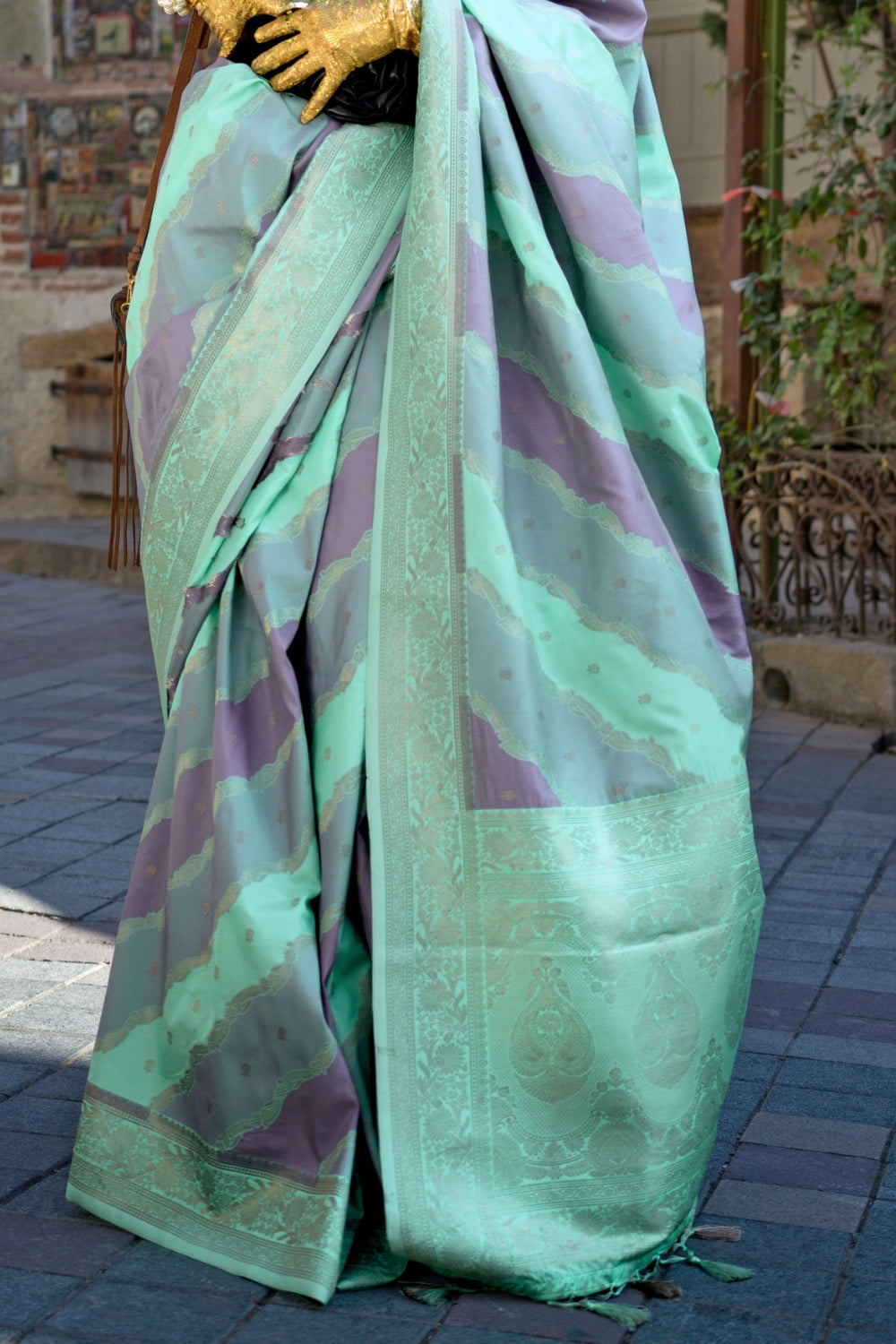 Mint and Mauve Kimbus saree in rangkaat katan silk, designed with wave-striped motifs and a dramatic tassel pallu. Best styled for sangeet and fashion-forward fusion ceremony celebrations. This image captures the back drape focus revealing pallu finesse and motif richness, ideal for visualizing festive elegance, designer appeal, and modern styling inspiration. Perfect for online shoppers seeking detailed previews before purchase, enhancing saree visual merchandising and SEO-rich product display strategy.   