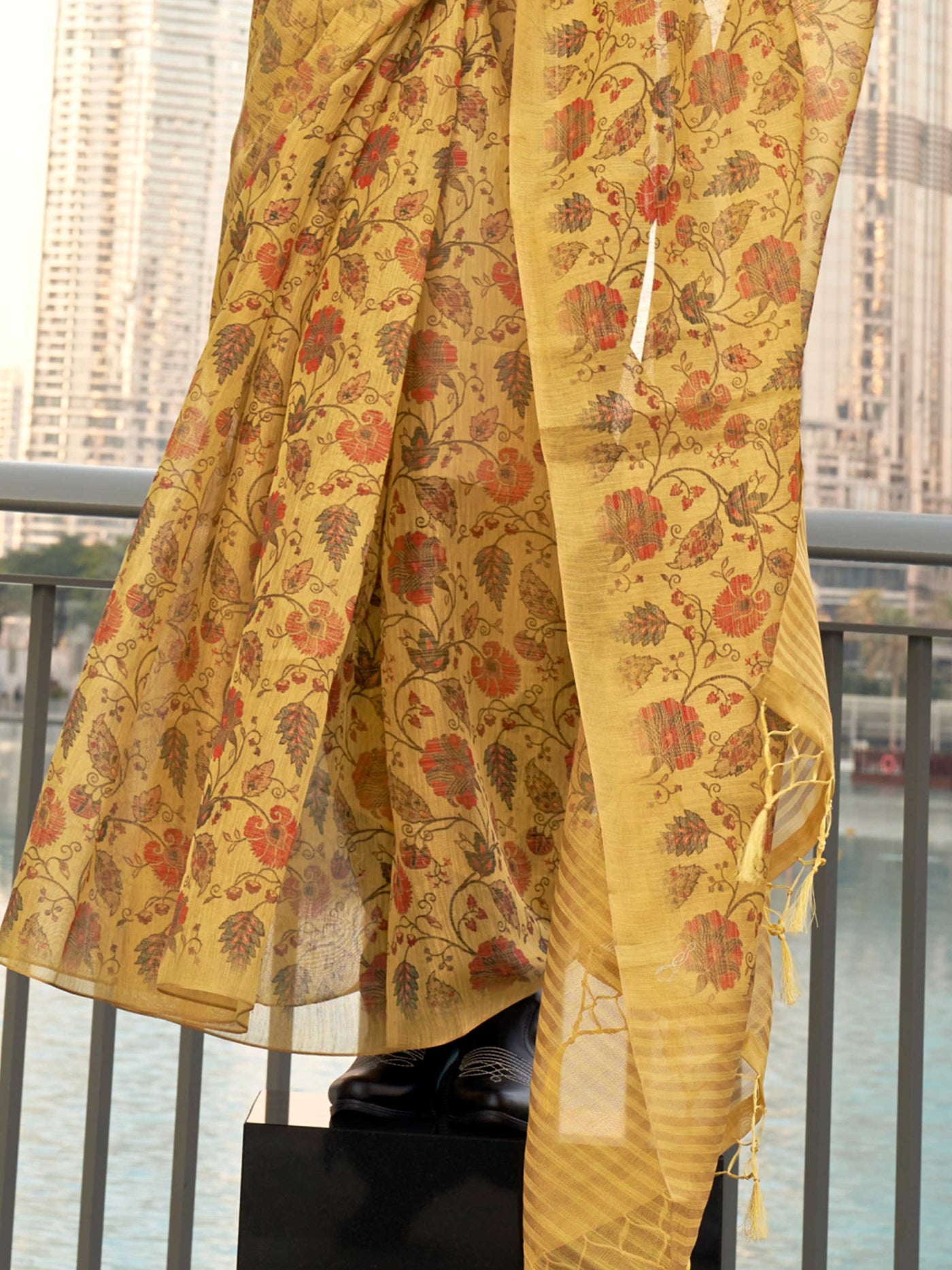 Yellow and Burnt Orange zari tissue saree with printed floral motifs and zari pallu This image captures the back drape focus revealing pallu finesse and motif richness, ideal for visualizing festive elegance, designer appeal, and modern styling inspiration. Perfect for online shoppers seeking detailed previews before purchase, enhancing saree visual merchandising and SEO-rich product display strategy.                                                                                                            