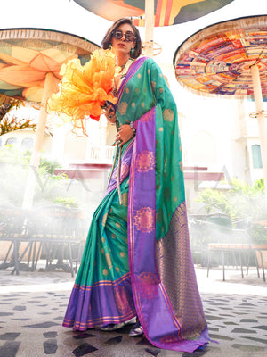 Emerald Green–Purple satin silk saree featuring woven zari mandala motifs, contrast pallu and elegant festive finish. Festive Emerald Green–Purple saree in soft satin silk with intricate weaving and a graceful two-tone blend.