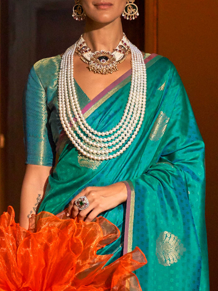 Teal Blue–Gold silk saree photographed in heritage setting with antique floor and floral wallpaper. Back fall view showing the dramatic zari pallu and matched blouse of Teal Blue–Gold saree..