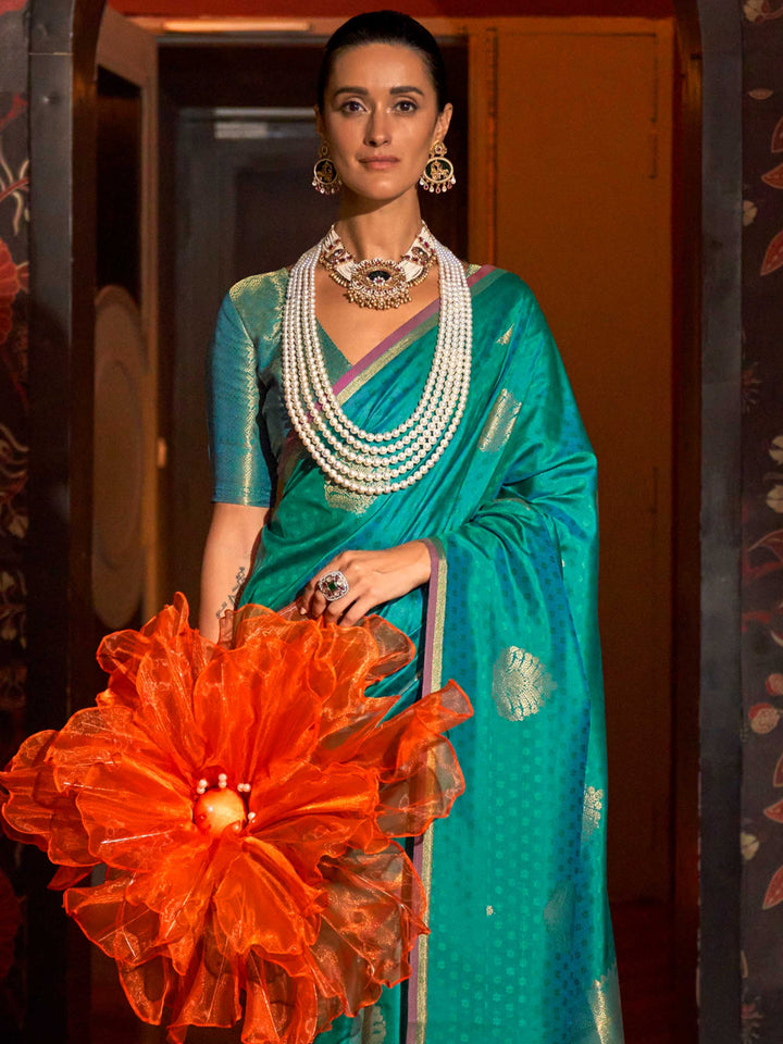 Soft satin silk texture and pleats of Teal Blue–Gold saree flowing into zari-drenched pallu. Close-up of zari woven motifs on Teal Blue–Gold banarasi saree with luxurious sheen..