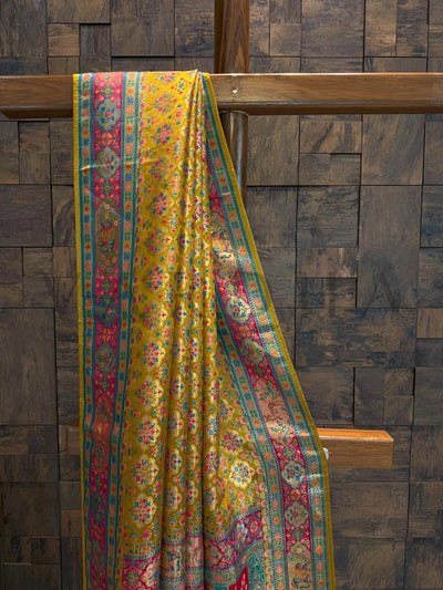 Colorful patterned fabric draped over a wooden rod against a wooden paneled wall.