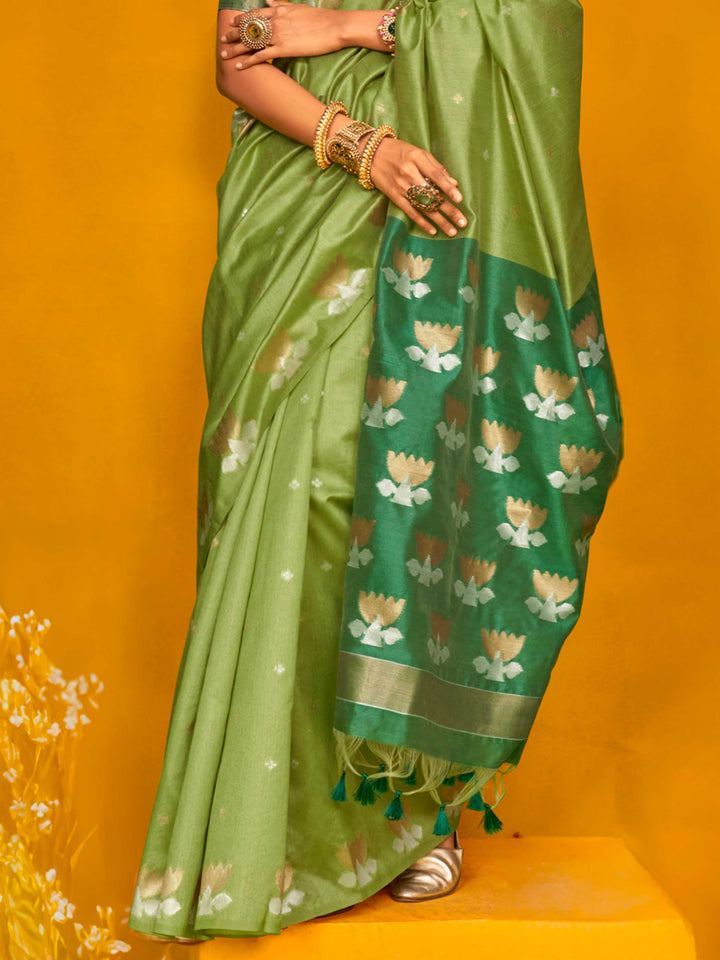 Leaf Green–Teal Green feathersoft tussar silk saree featuring woven lotus motifs and soft pallu, styled for festive rituals with a breathable finish. Leaf Green–Teal Green feathersoft tussar silk saree featuring woven lotus motifs and soft pallu, styled for festive rituals with a breathable finish..