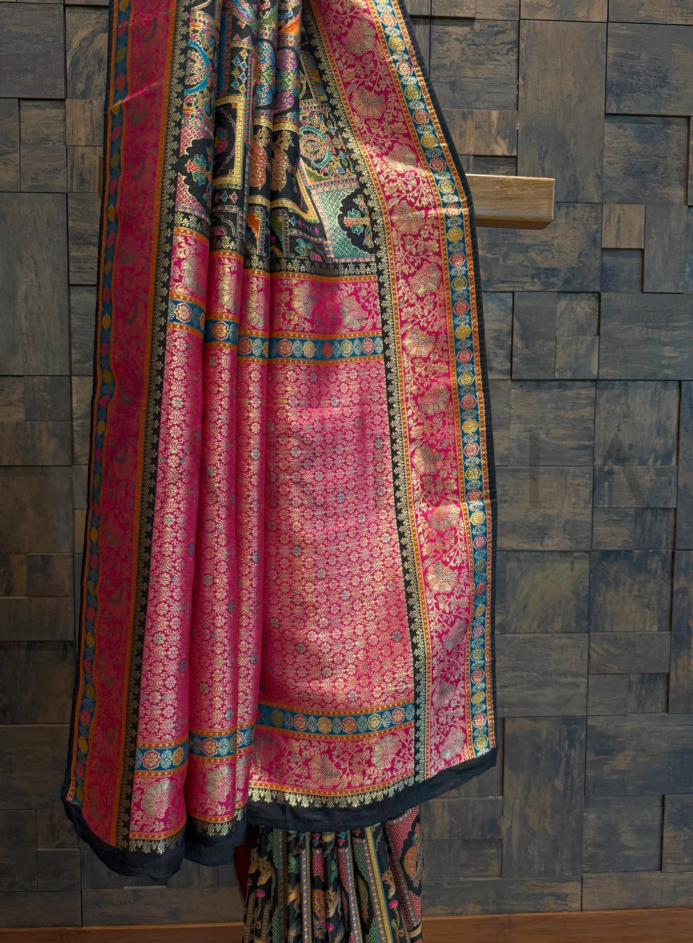 Colorful traditional saree draped over a wooden surface with a textured wall background