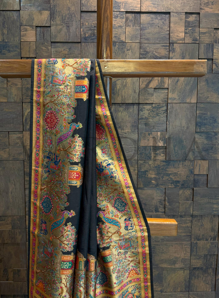 Colorful saree draped over a wooden rod against a wooden paneled wall.