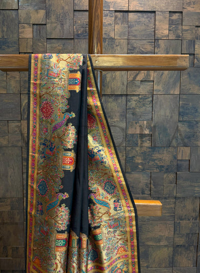 Colorful saree draped over a wooden rod against a wooden paneled wall.