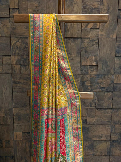 Colorful patterned fabric draped over a wooden rod against a wooden paneled wall.