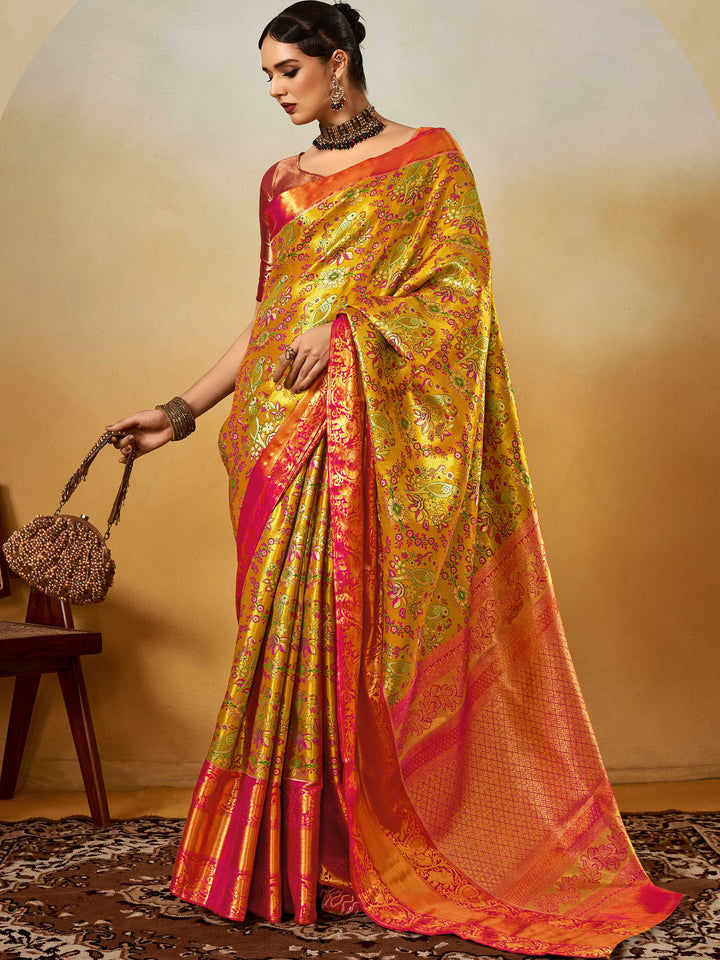Yellow–Pink Banarasi satin silk saree with zari work and woven parrot motifs, styled for traditional Indian wedding rituals with luxury finish. Yellow–Pink Banarasi satin silk saree with zari work and woven parrot motifs, styled for traditional Indian wedding rituals with luxury finish..
