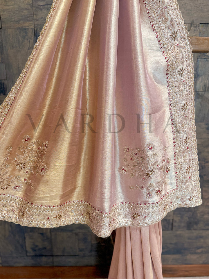 Lace dress on a wooden stand against a textured wall. Pallu view of the saree showing luminous tissue sheen with rich zardozi and floral embellishments.