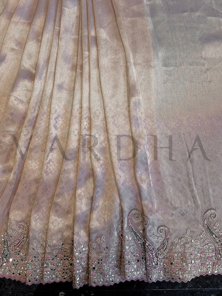 Close-up of a fabric with intricate patterns and 'Vardha' branding. Border shot showing intricate stone and mirror grid work in blush, silver, and green