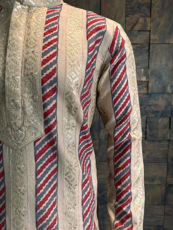 Traditional embroidered garment with red and blue patterns on a textured wall background Side view of Embroidered Party Wear Kurta showing Vertical Sequin Panels.