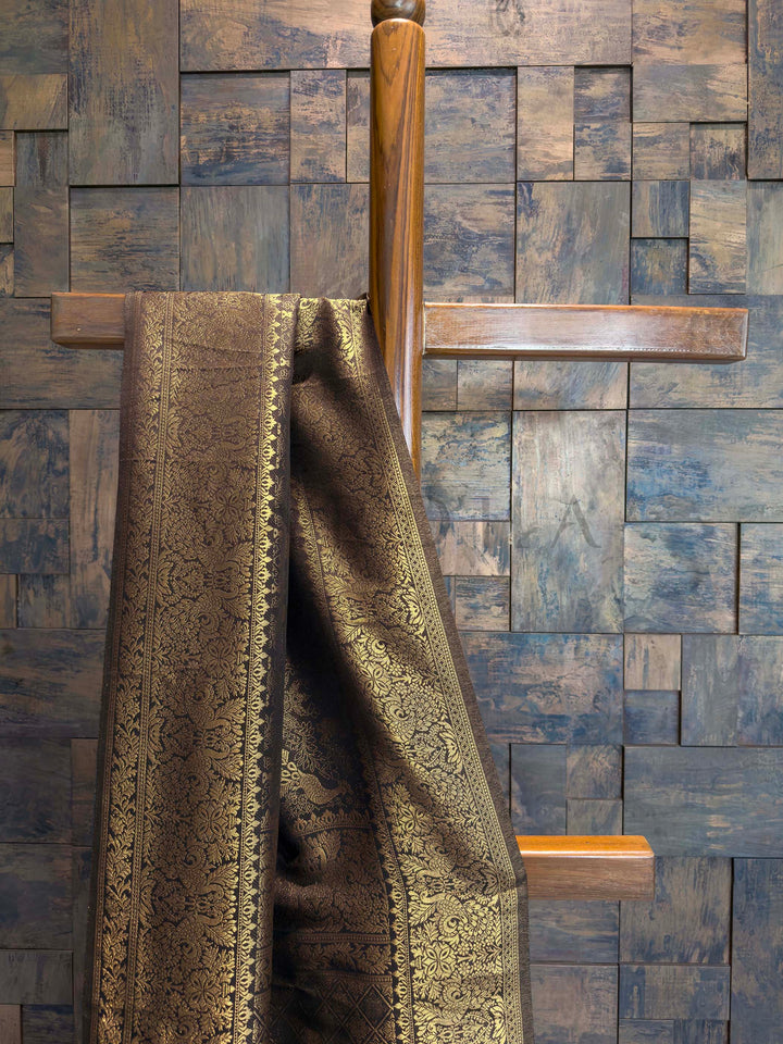 Black textured fabric draped over a wooden rod against a wooden paneled wall. Banarasi-style Black saree with heritage zari peacocks and intricate brocade border shown on mannequin